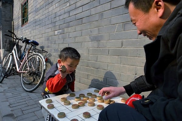 Father and son playing Chinese chess in the hutongs